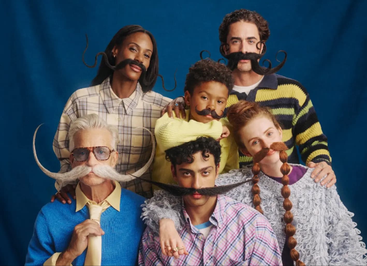 Six Stash members with dramatic moustaches posed together against a blue backdrop