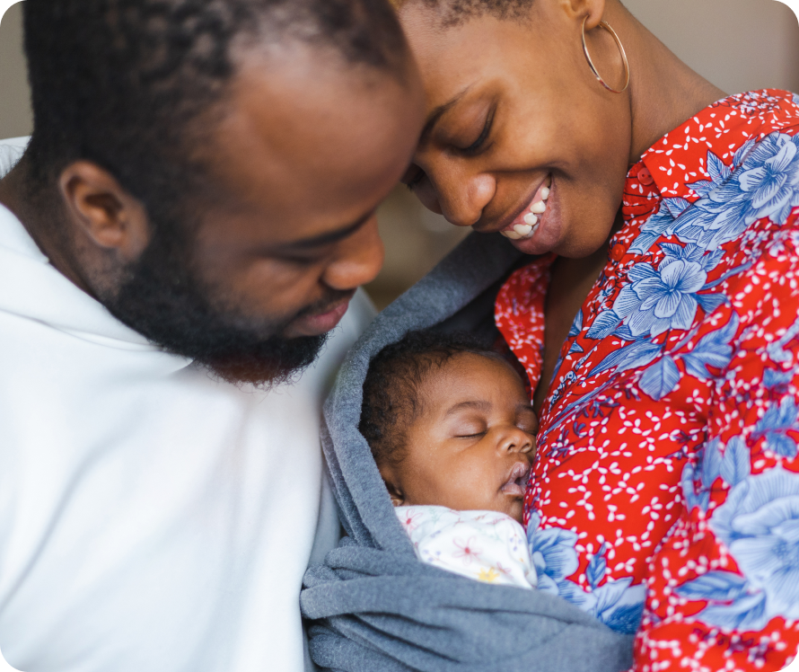 Two parents holding their baby while smiling.