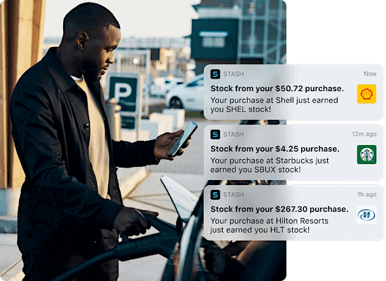 A man filling his car with gas while checking his phone notifications.